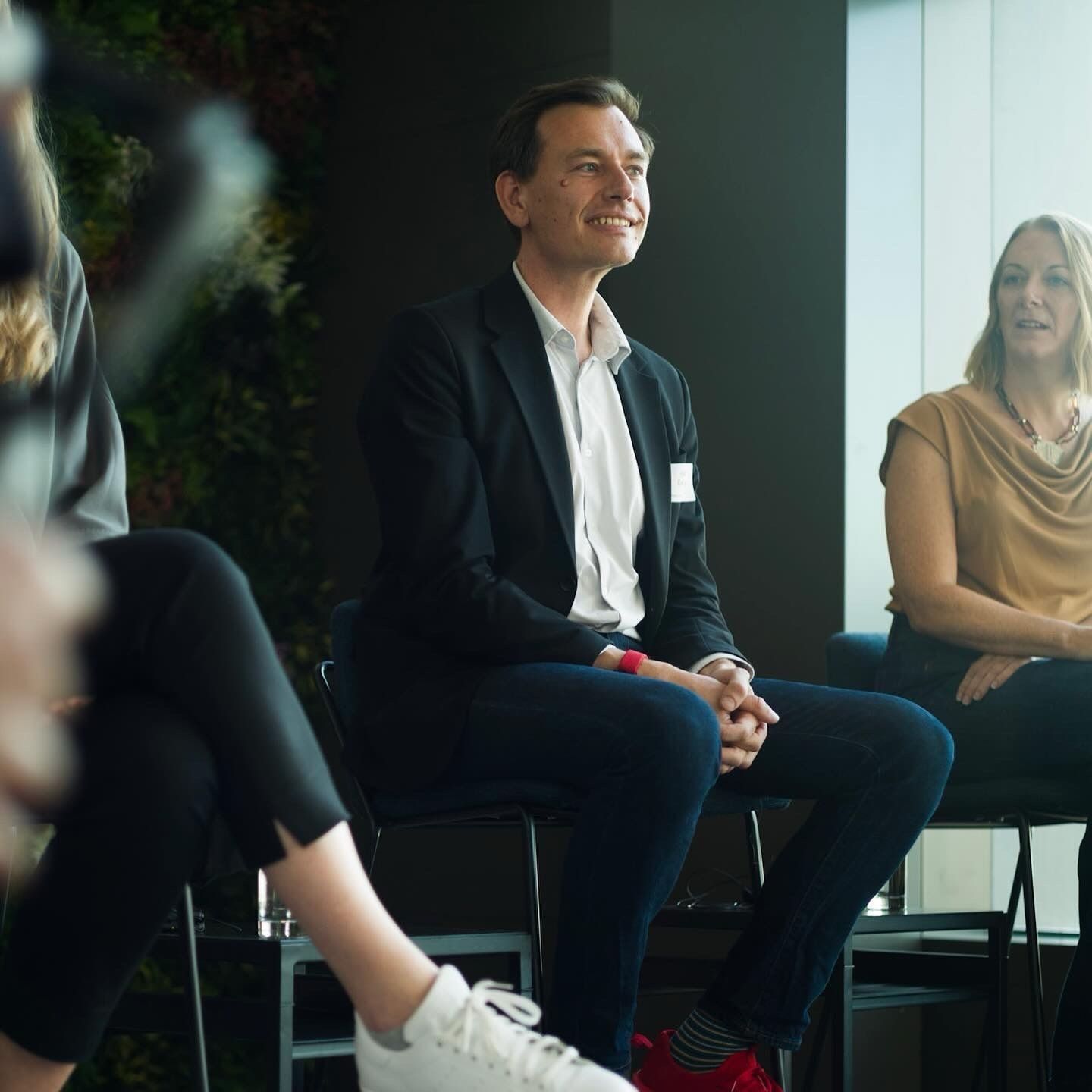 A speaker seated on stage, smiling, at a previous Design Leaders event